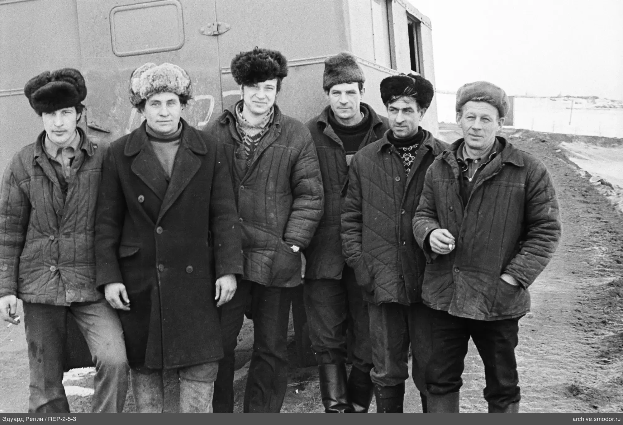 Группа мужчин у металлического фургона