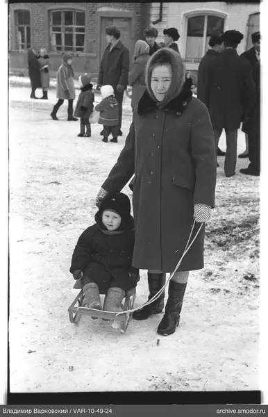 Frau mit Schlitten und Kind im Schnee