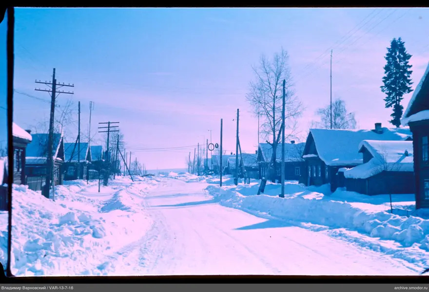 Snow-covered street with wooden houses