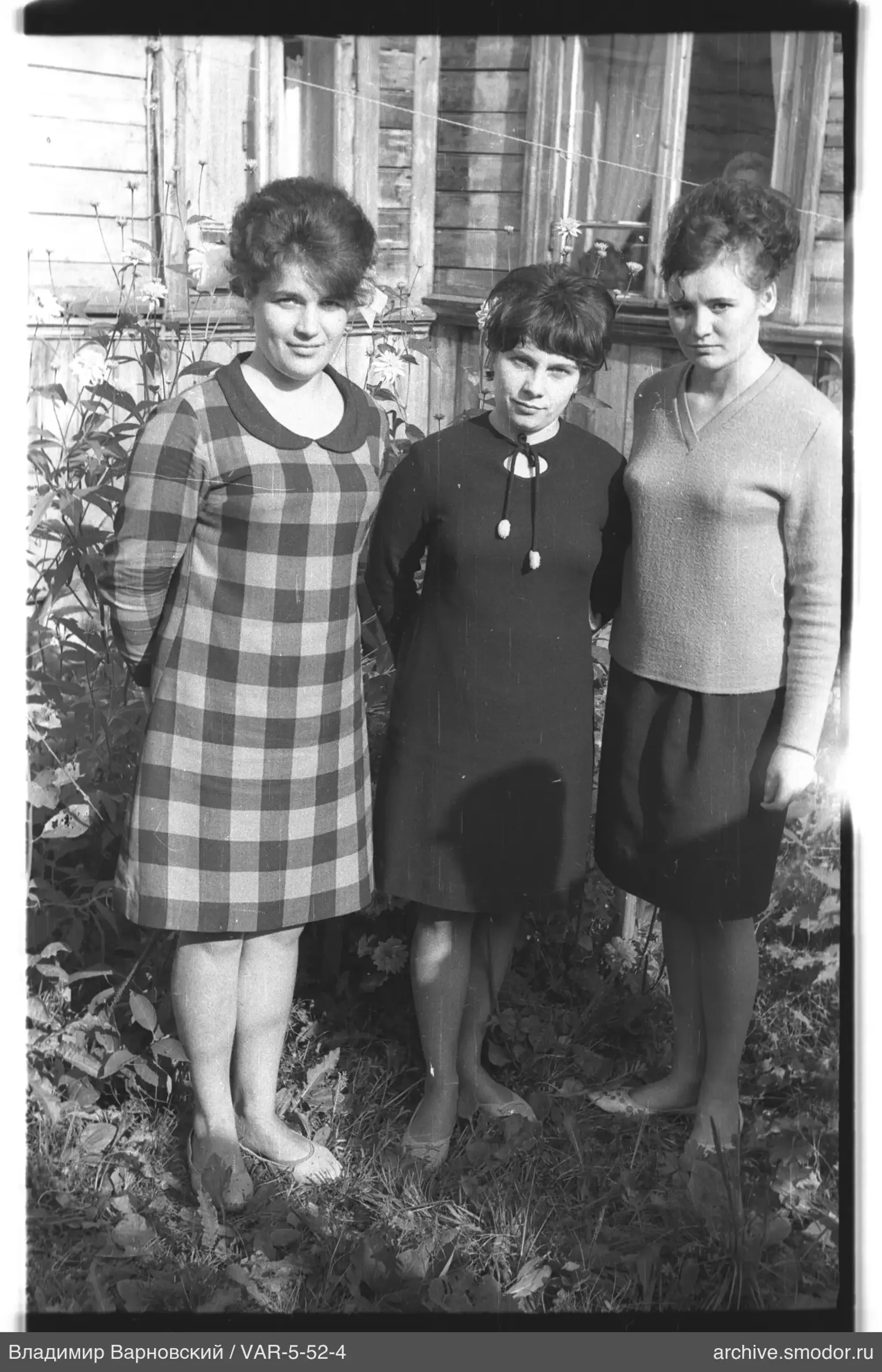Three women near a wooden house