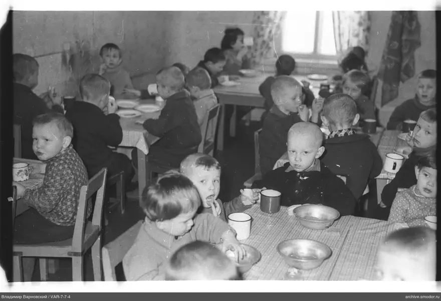 Children sitting at tables with dishes