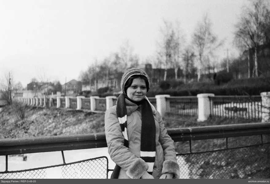 Frau in Winterkleidung an einem Metallgeländer