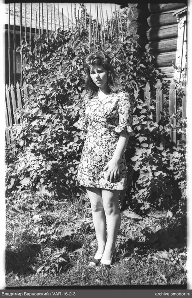 Frau neben Holzzaun und Haus