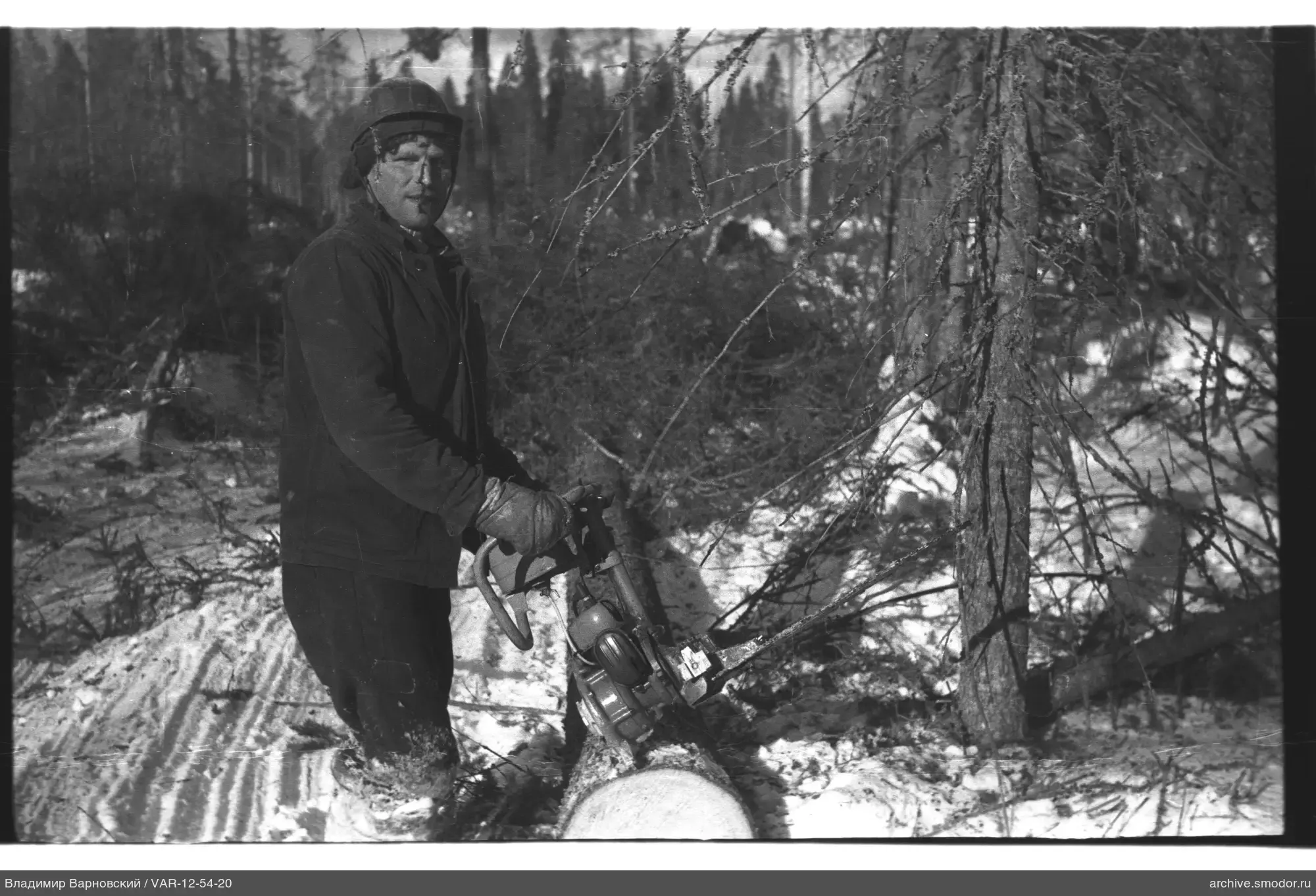 Mann mit Motorsäge im verschneiten Wald