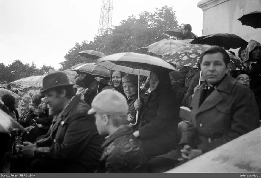 Gruppe von Menschen auf Tribünen mit Regenschirmen