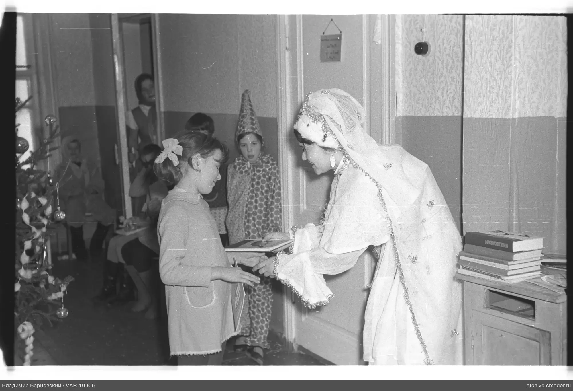 Woman handing a book to a girl