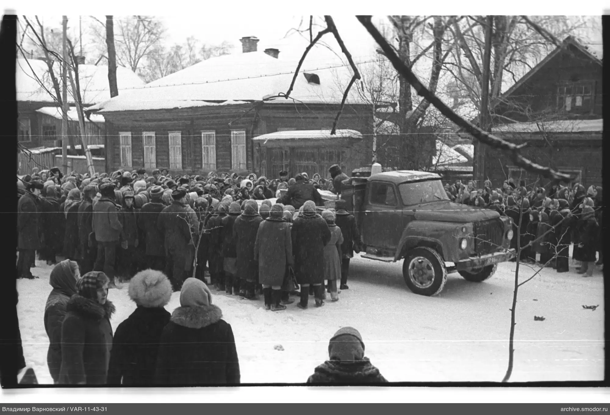 Gruppe von Menschen vor Holzhäusern im Schnee