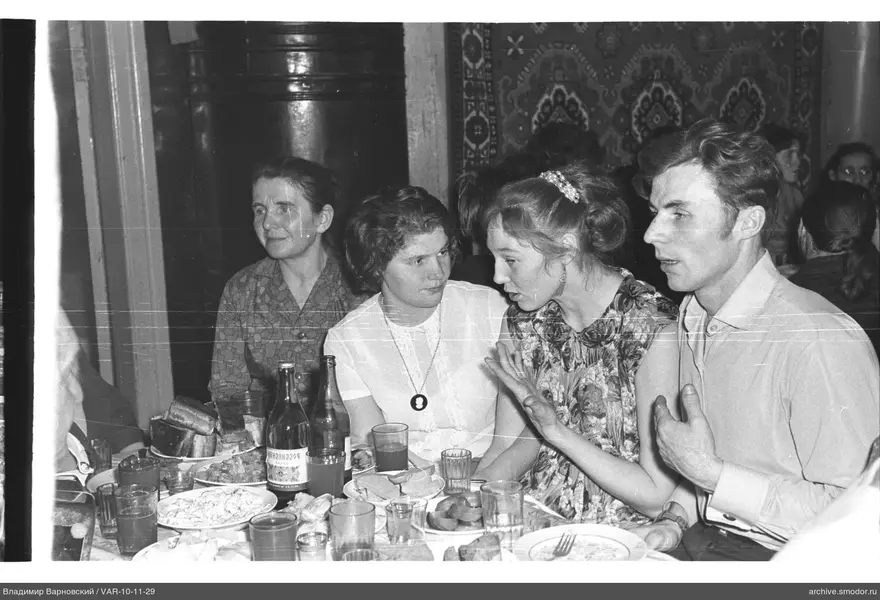 Group of people sitting at a table with dishes and bottles