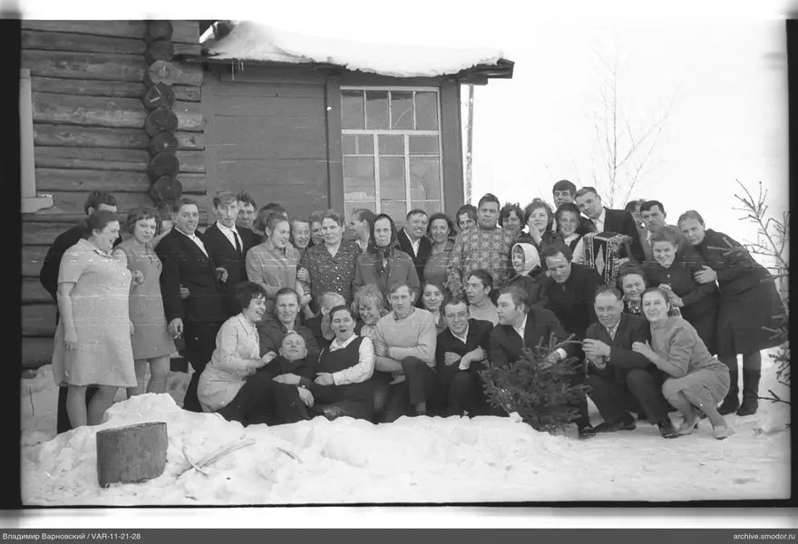 Gruppe von Menschen bei einem Holzhaus