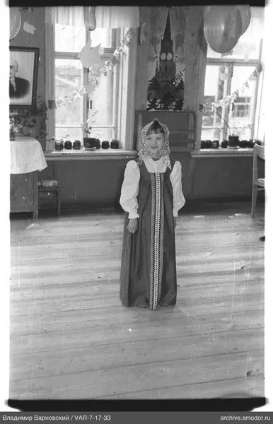 Mädchen in Kleid und Kopftuch im Raum
