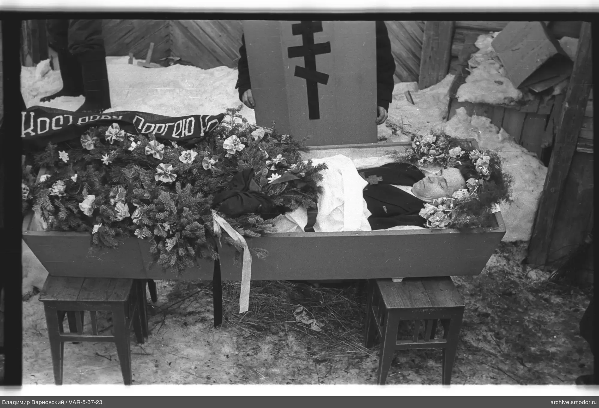Mann im Sarg mit Kranz und Kreuz