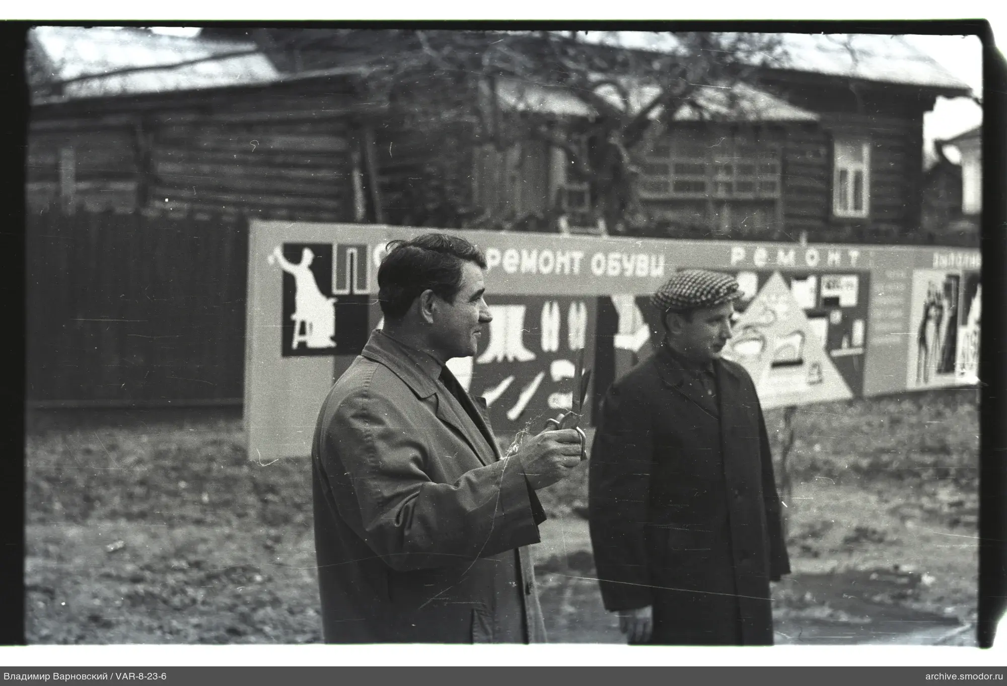 Two men on the street near a billboard