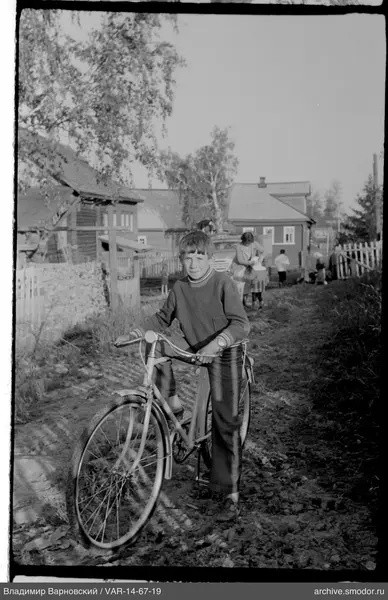 Boy with bicycle near wooden houses