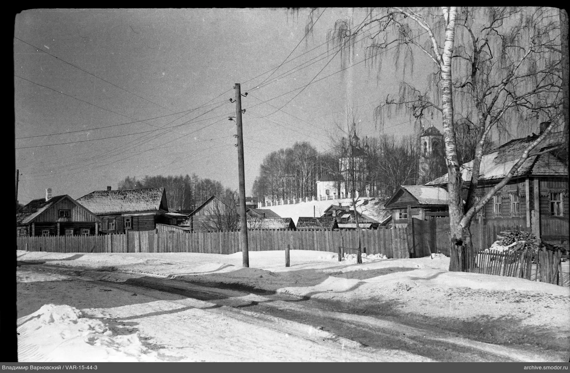 Заснеженная улица с деревьями и церковью