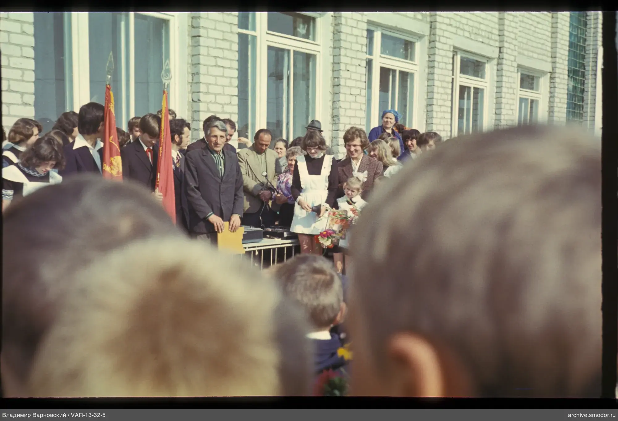 Gruppe vor Gebäude mit Fahnen und Kindern