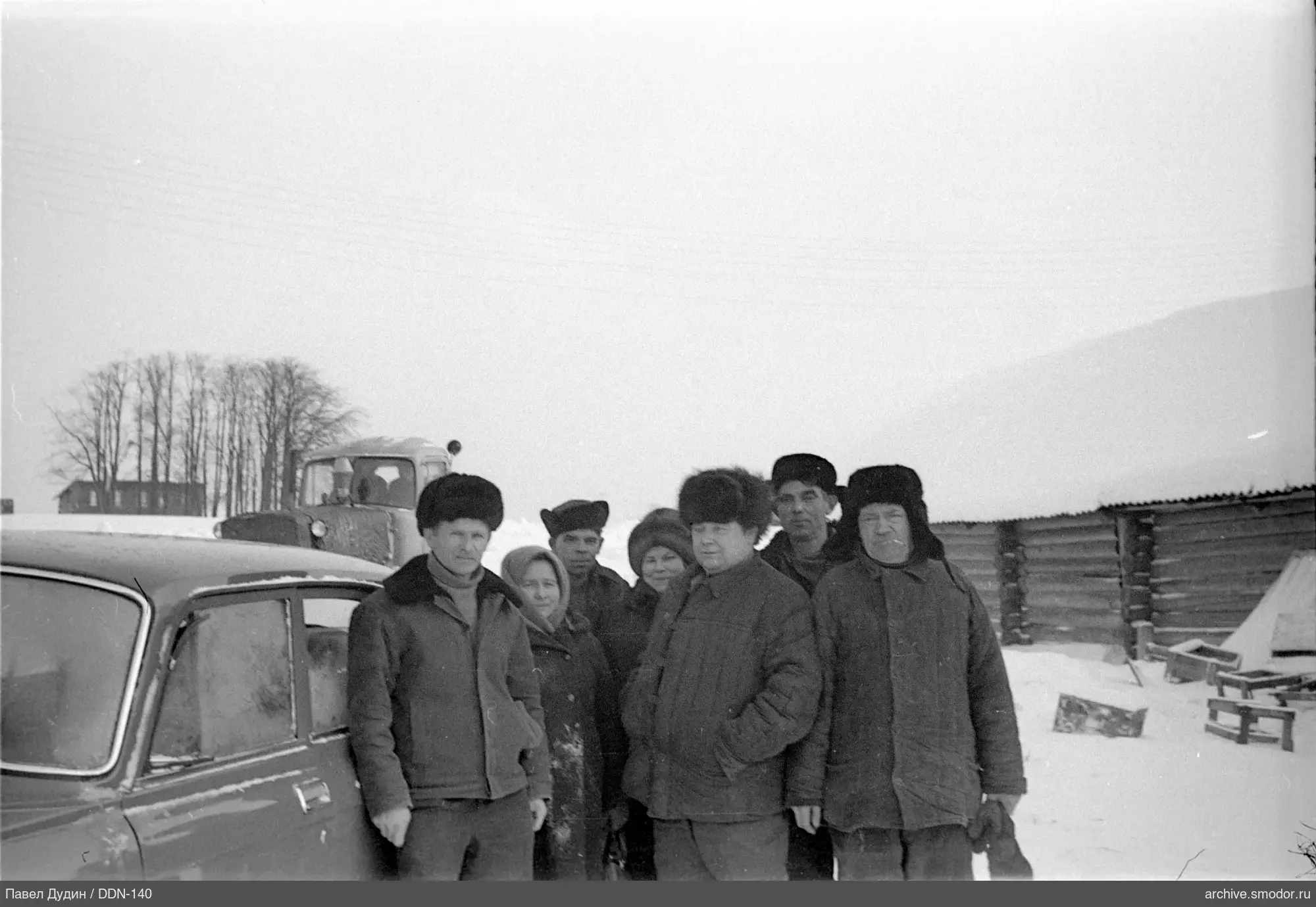 Gruppe von Menschen im Schnee neben einem Auto