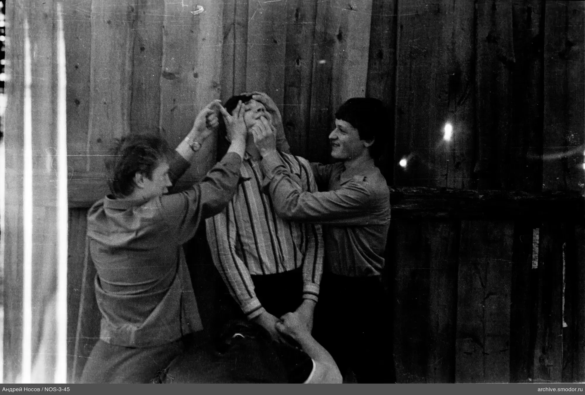 Группа людей у деревянной стены