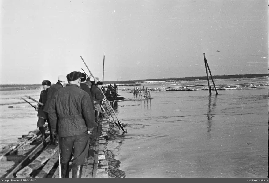 Männer mit langen Stangen am Fluss