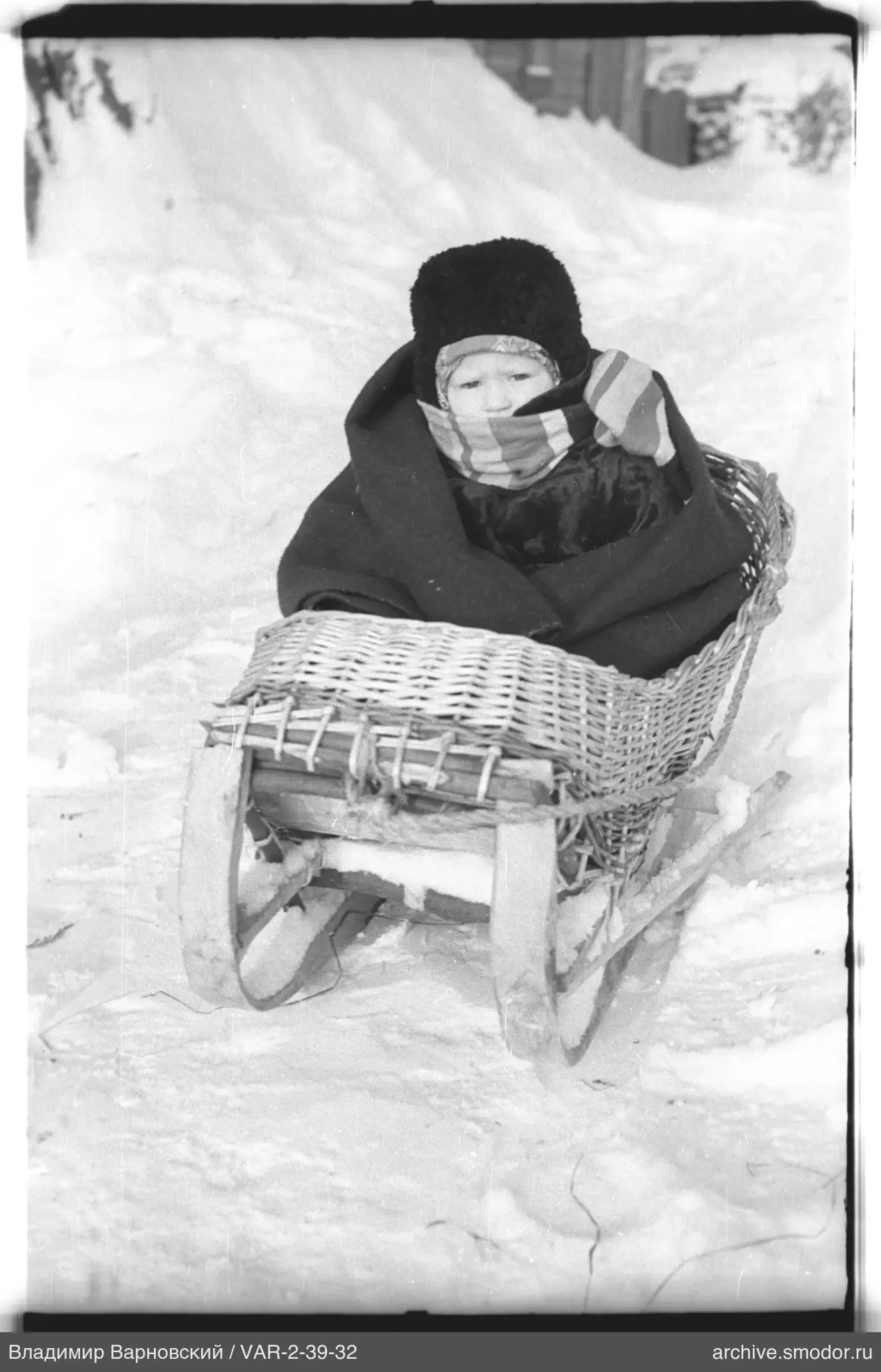 Kind im Korbschlitten im Schnee