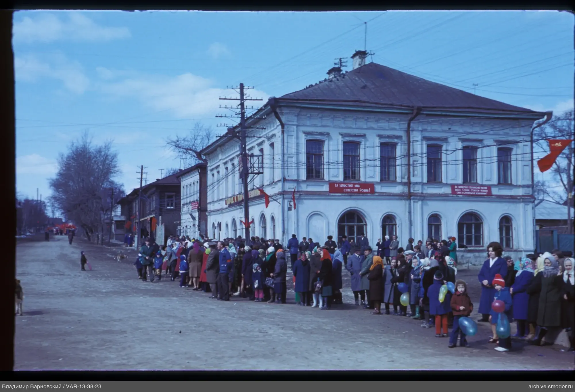 Gruppe von Menschen bei Gebäude mit Plakaten und Fahnen
