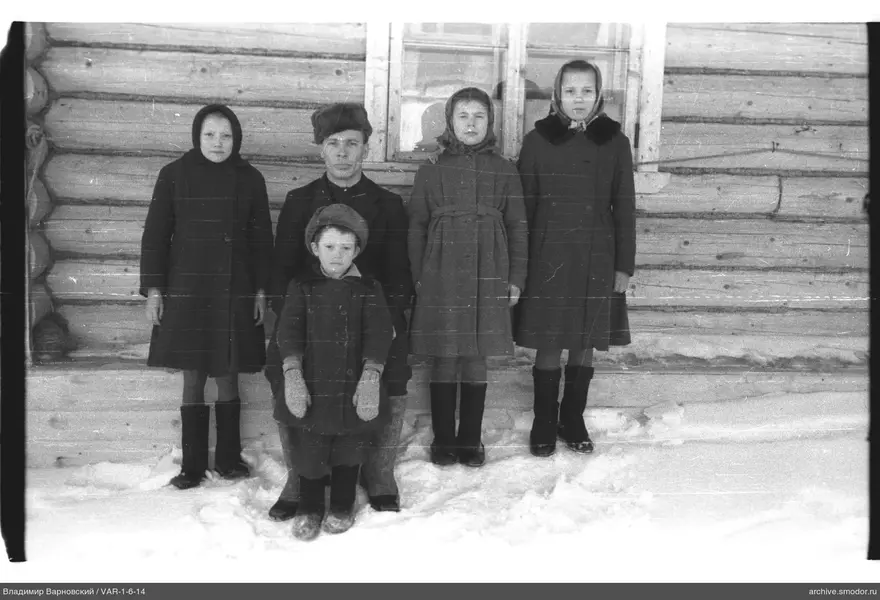 Gruppe von Menschen vor einer Holzhütte im Schnee