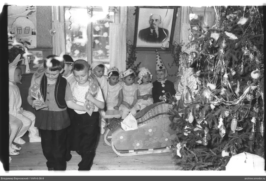 Kinder vor geschmücktem Weihnachtsbaum und Porträt