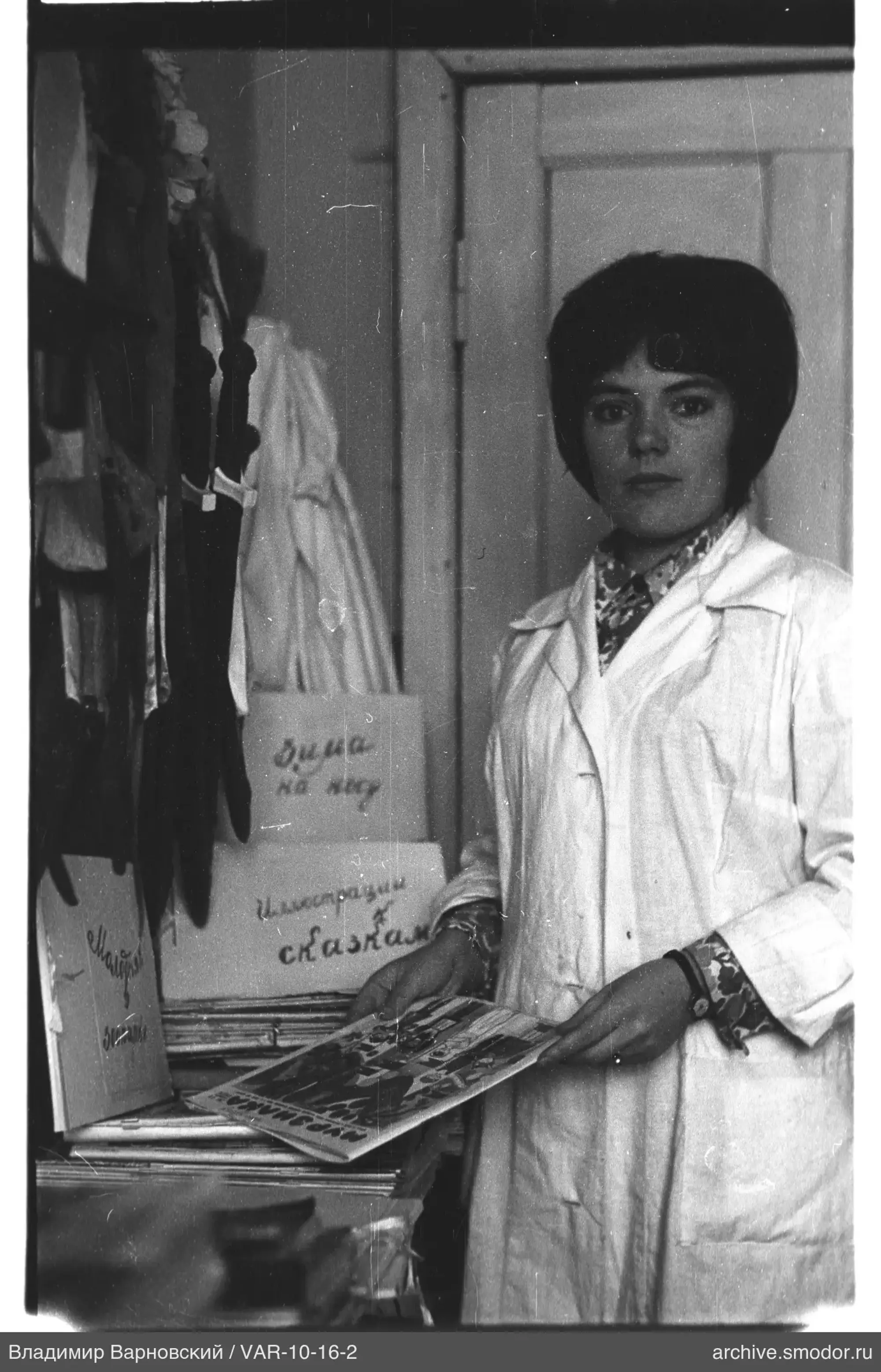 Женщина с журналом у стола с книгами