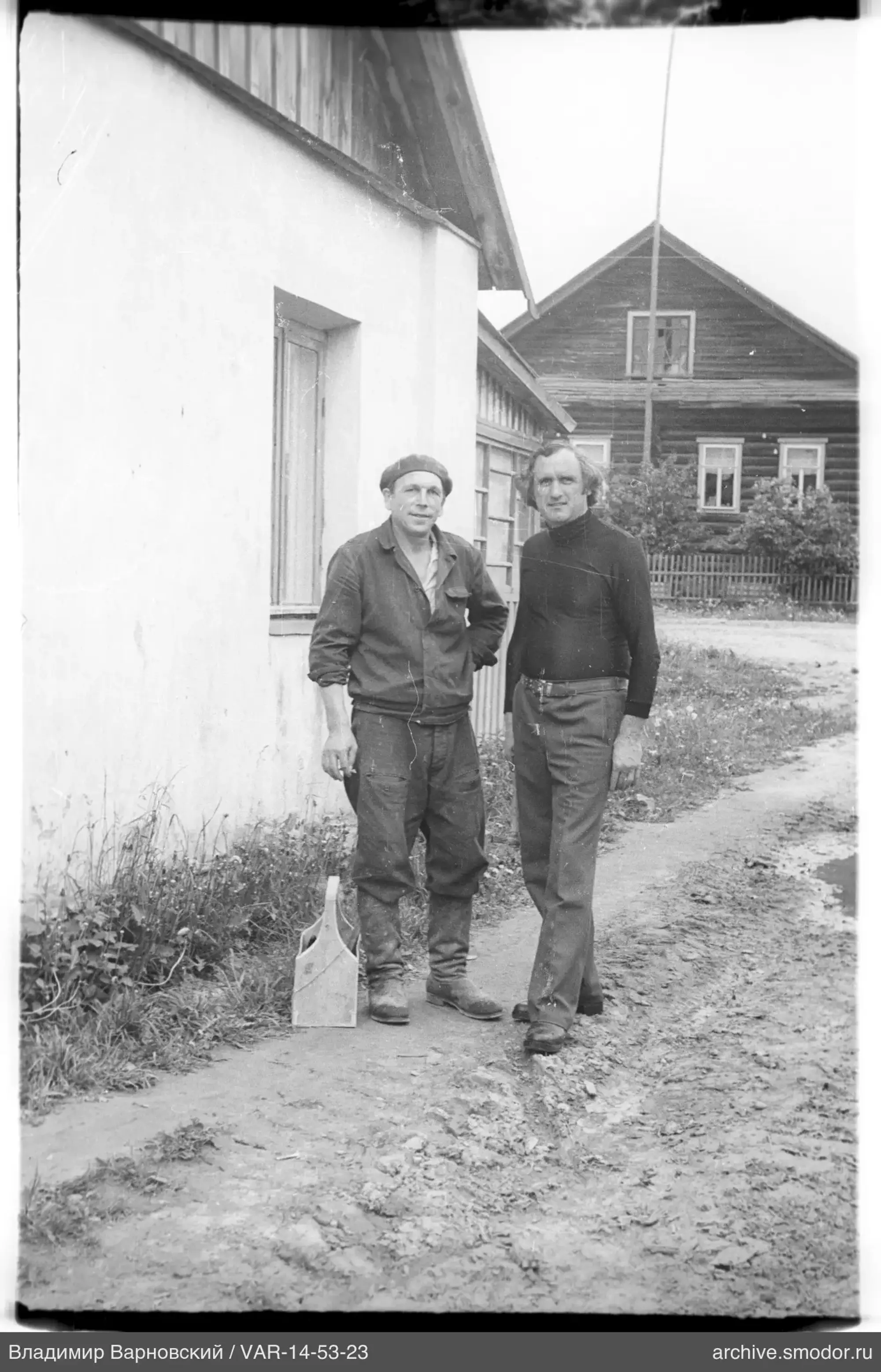Zwei Männer auf einem Feldweg neben einem Gebäude
