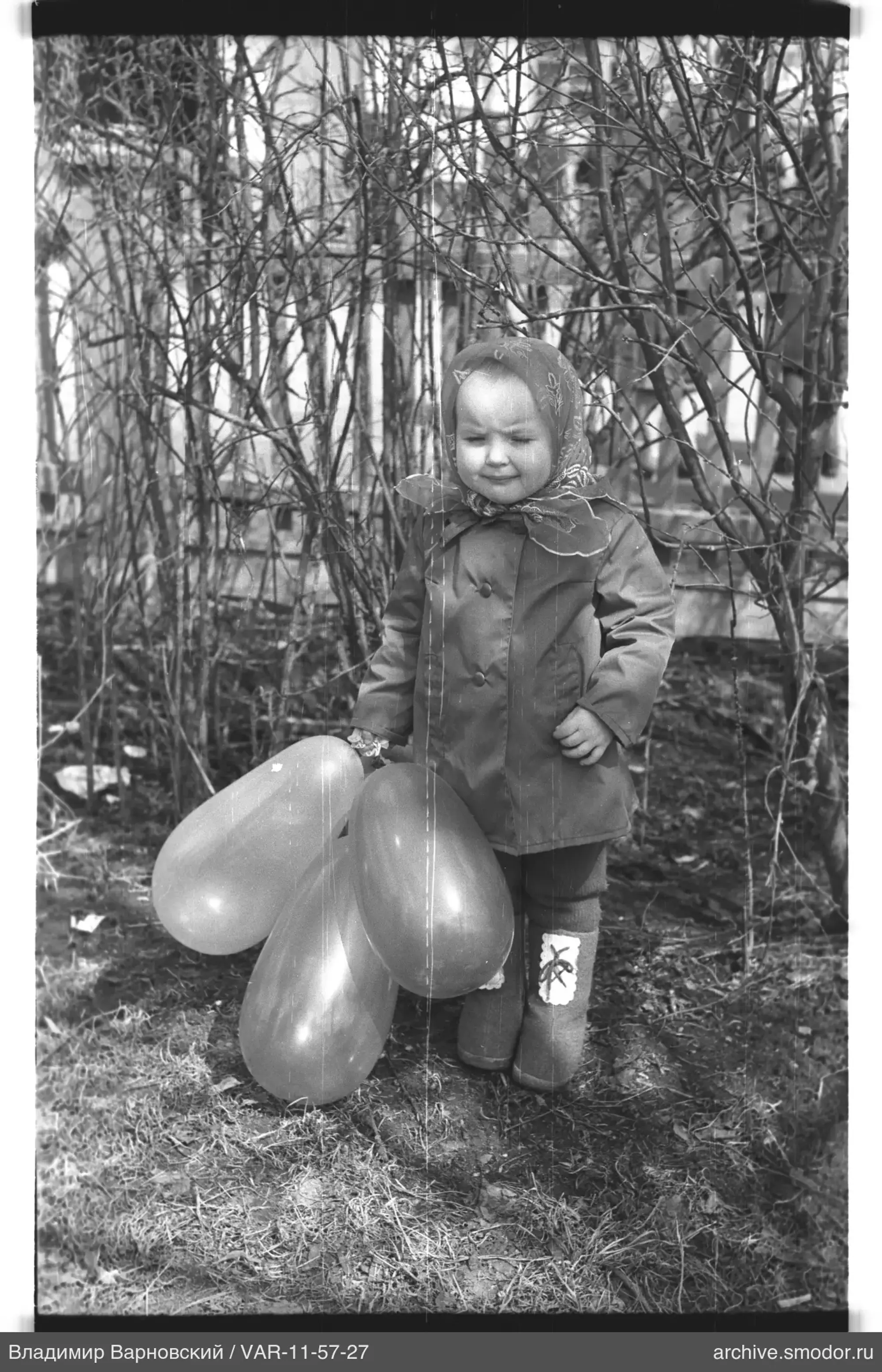 Kind mit Ballons bei Büschen
