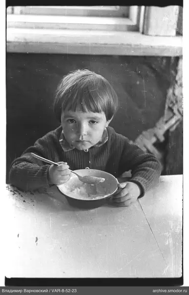 Child sitting at table with spoon and bowl