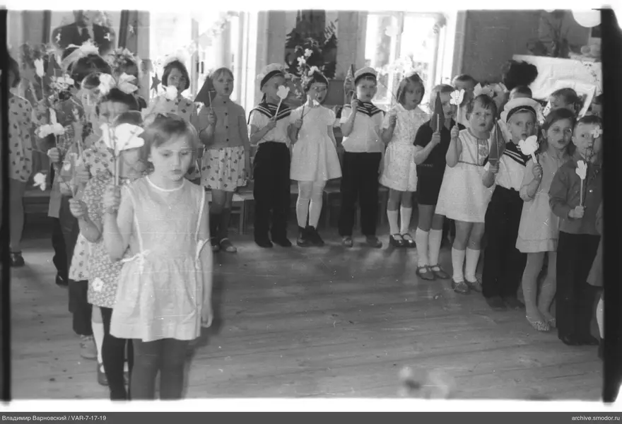 Gruppe von Kindern mit Papierblumen und Fahnen