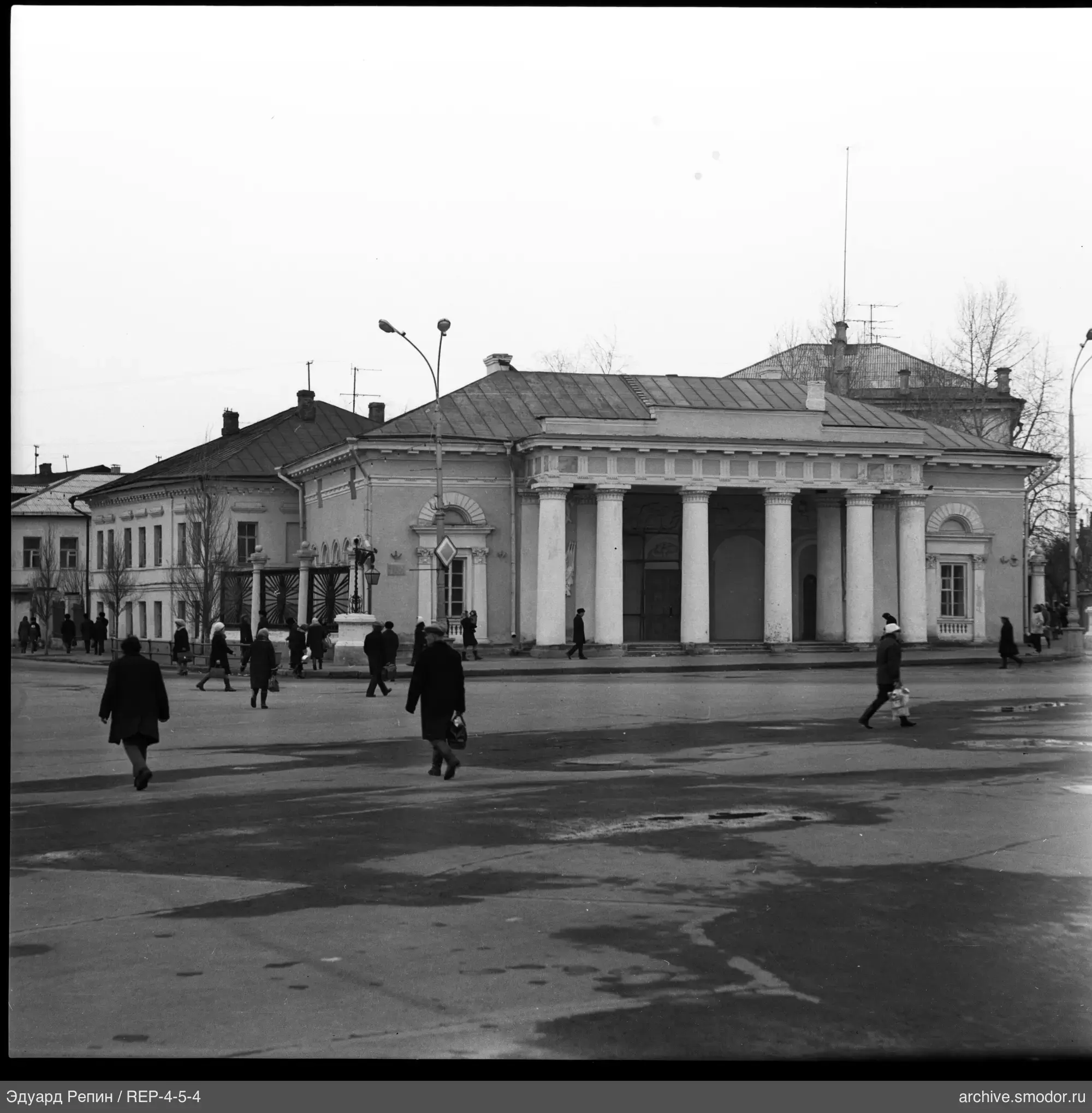 Building with colonnade and street with pedestrians