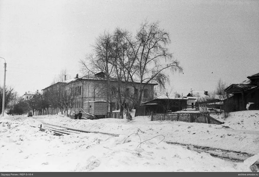 Verschneite Straße mit Gebäuden und Menschen