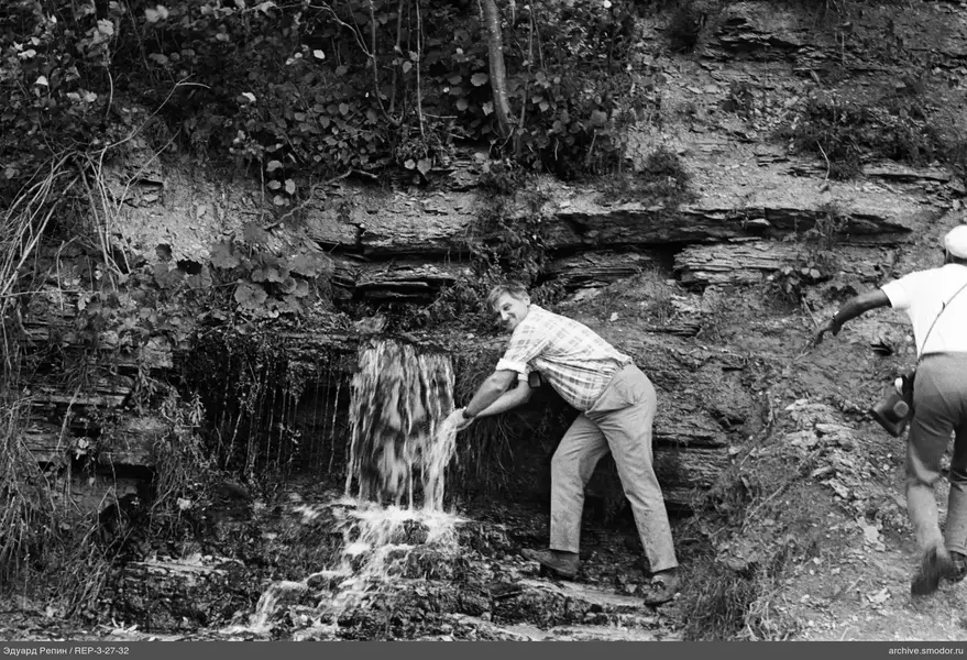 Zwei Männer an einer Felsklippe mit Wasserfall