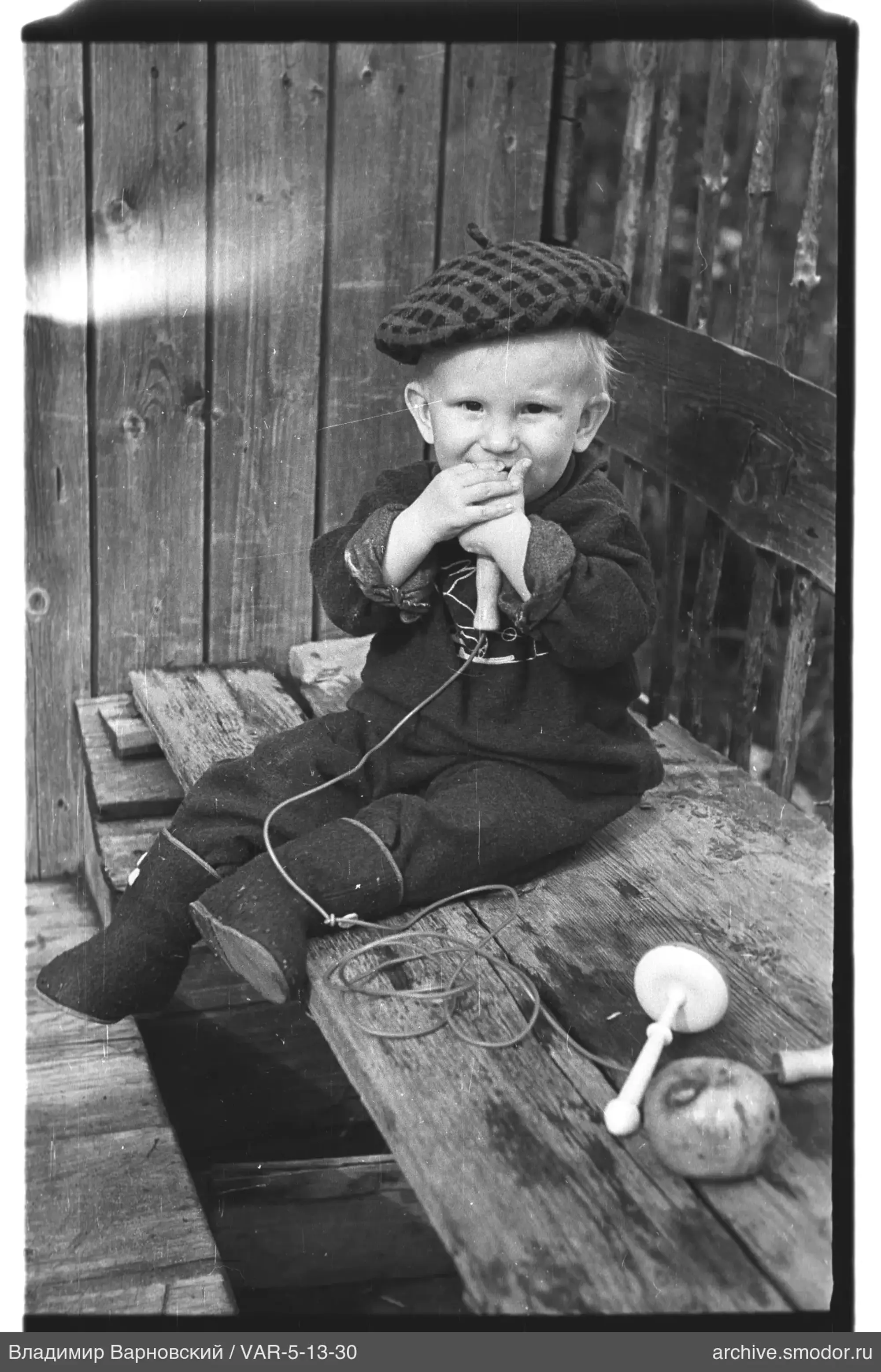 Child with toys by wooden wall