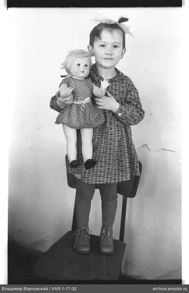 Mädchen mit Puppe auf Stuhl