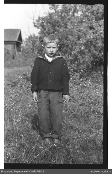 Junge in dunkler Jacke auf Gras
