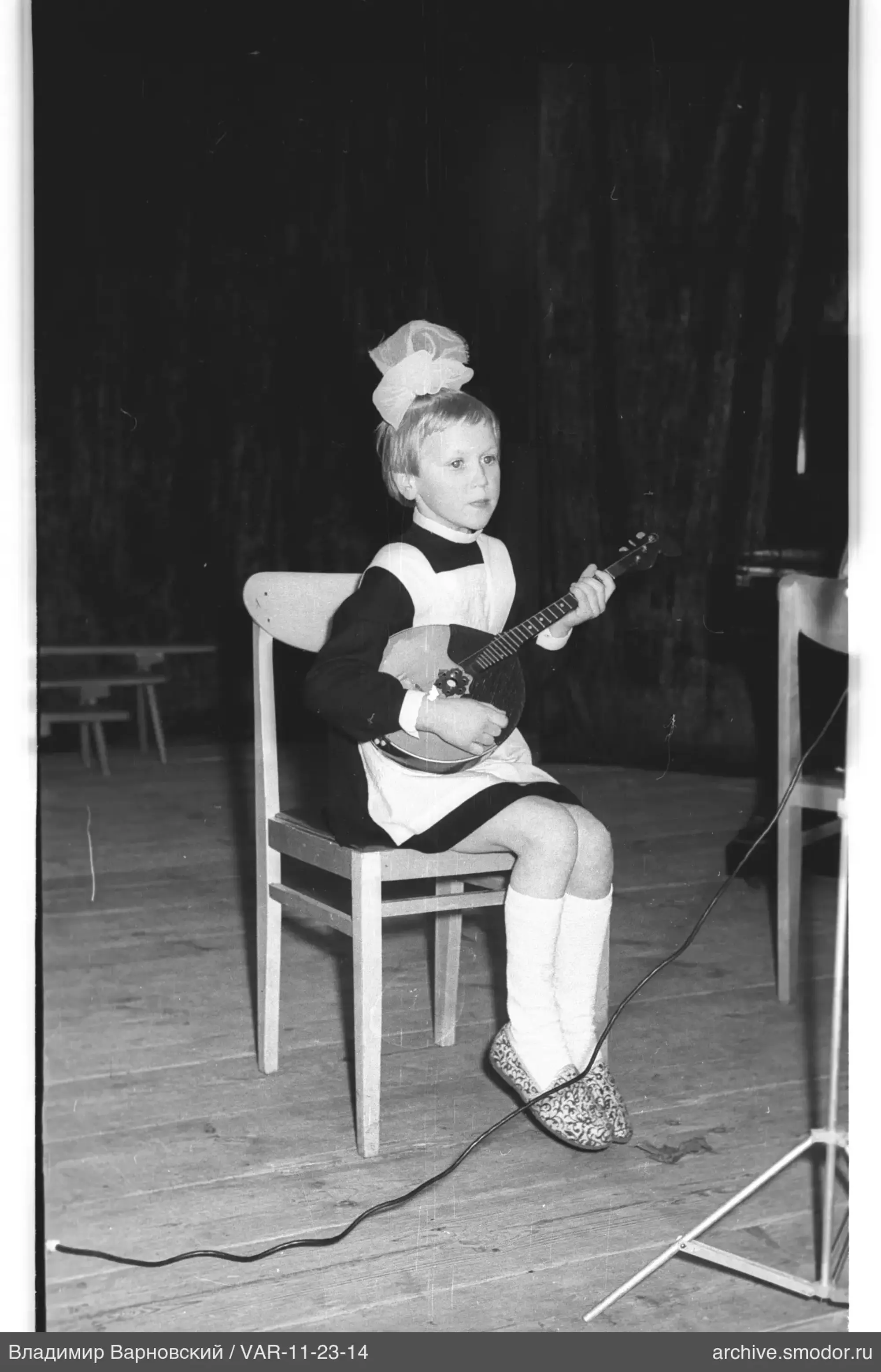 Child with balalaika on a chair