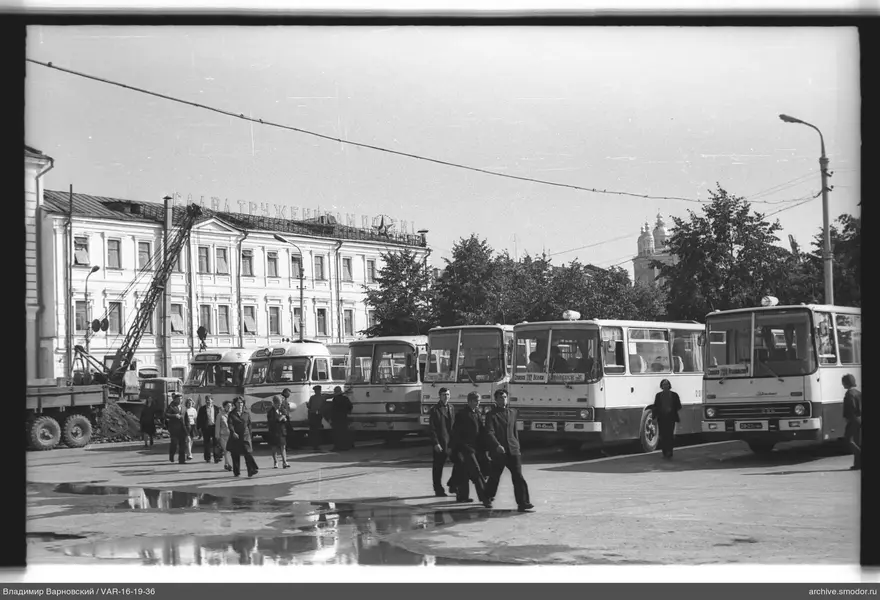 Group of people on square with buses