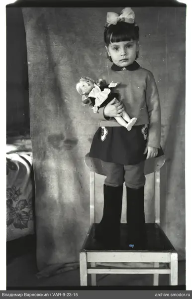 Mädchen mit Puppe auf Stuhl