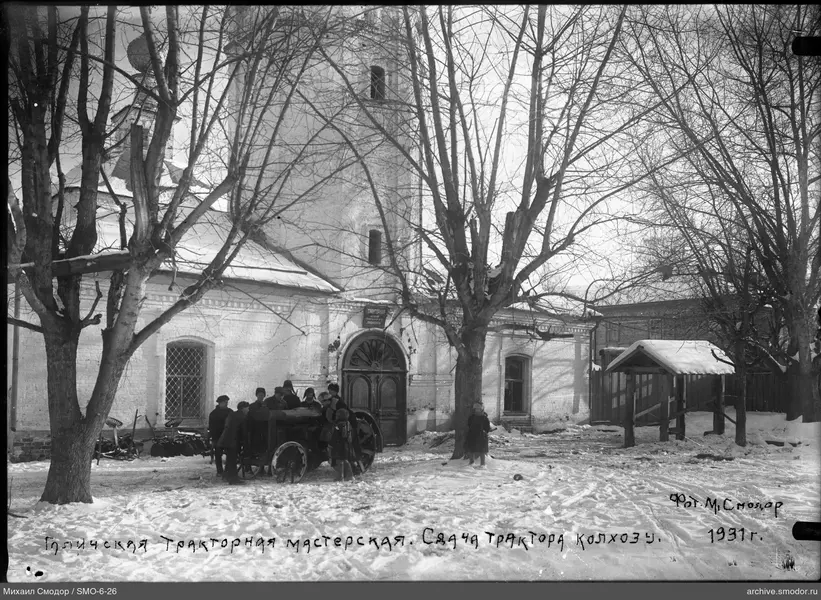 Мужчины и мальчики у трактора перед мастерской