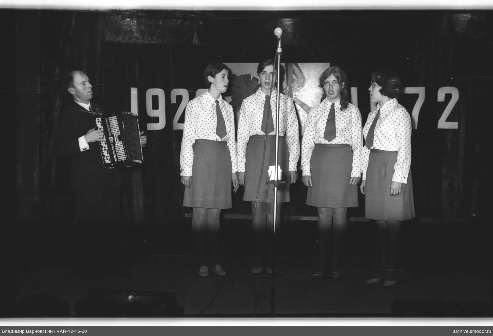Мужчина с аккордеоном и девушки на сцене