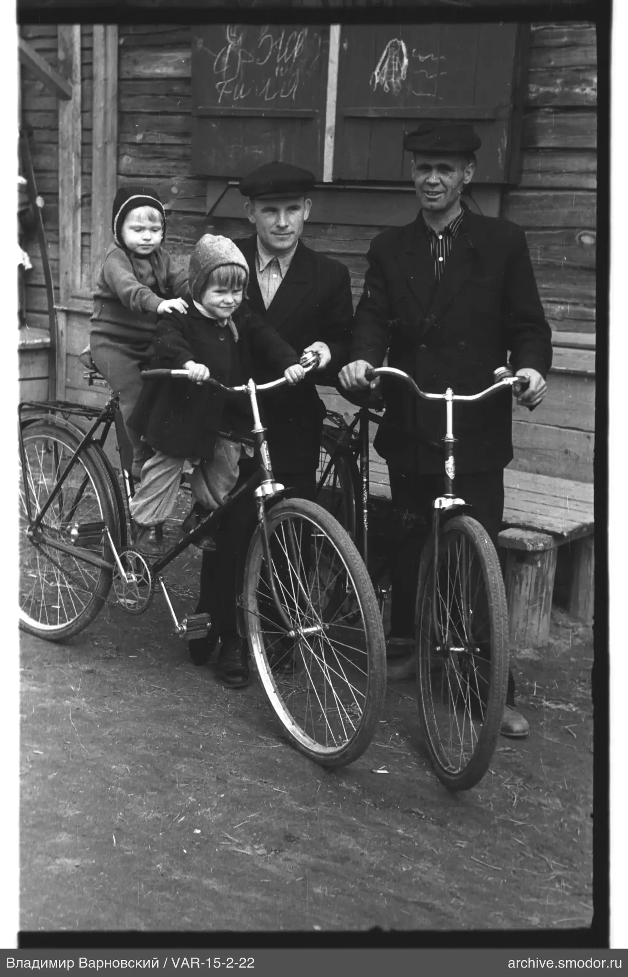 Gruppe mit Fahrrädern und Kindern vor einem Holzgebäude