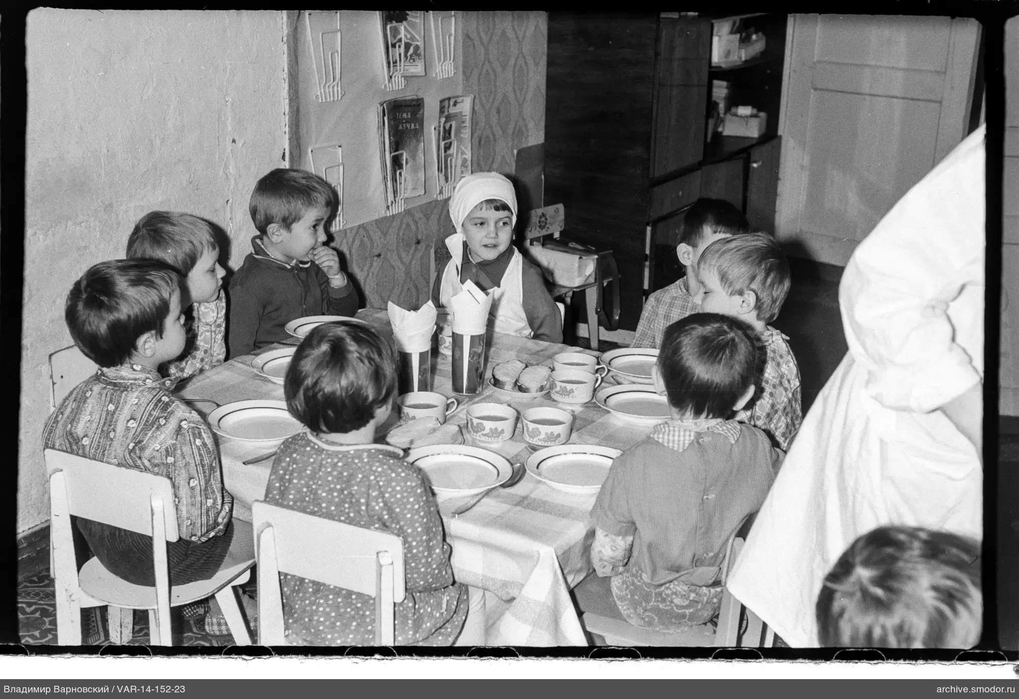Kinder am Tisch mit Person im weißen Kittel