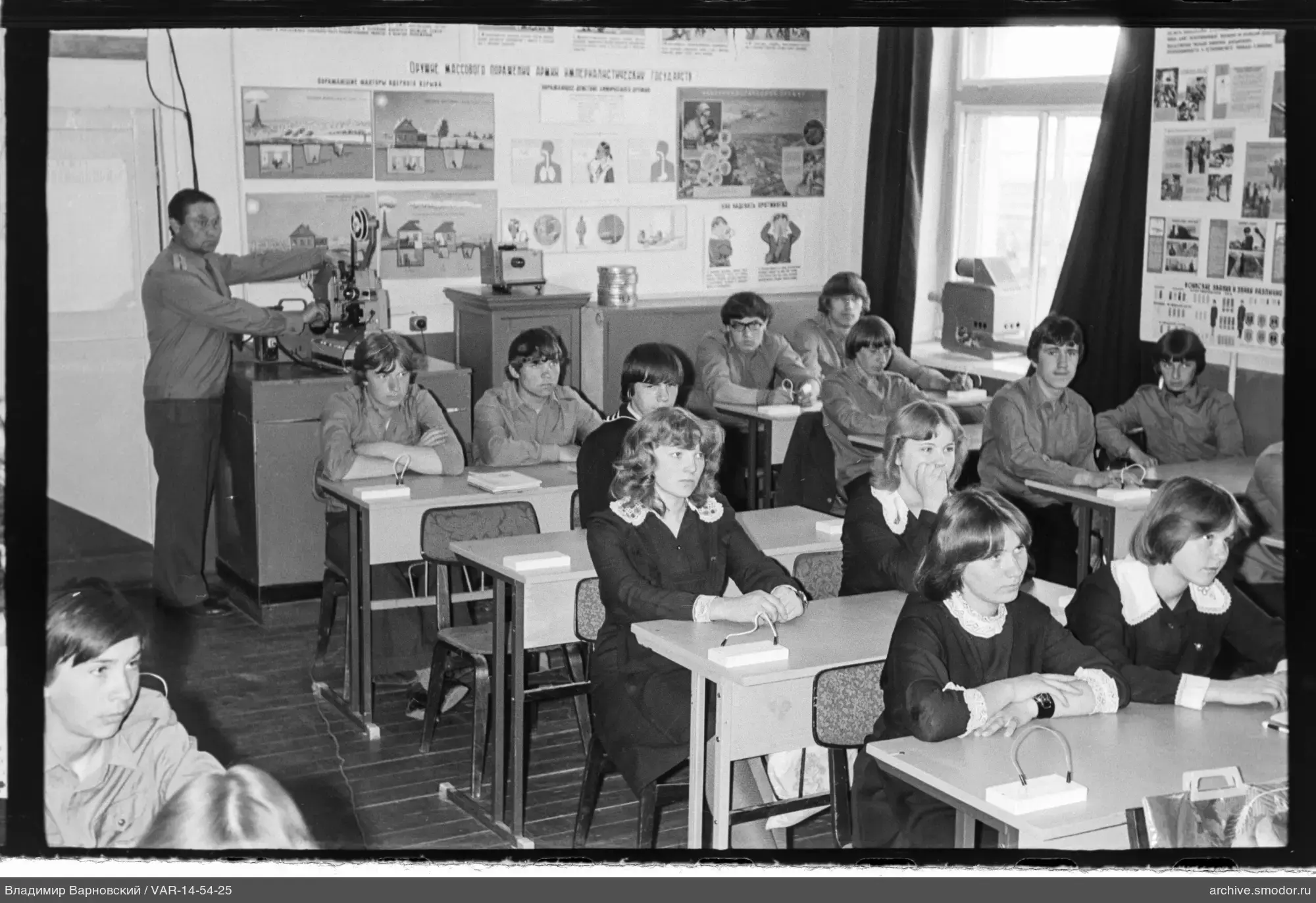 Ученики в классе с преподавателем и учебными плакатами