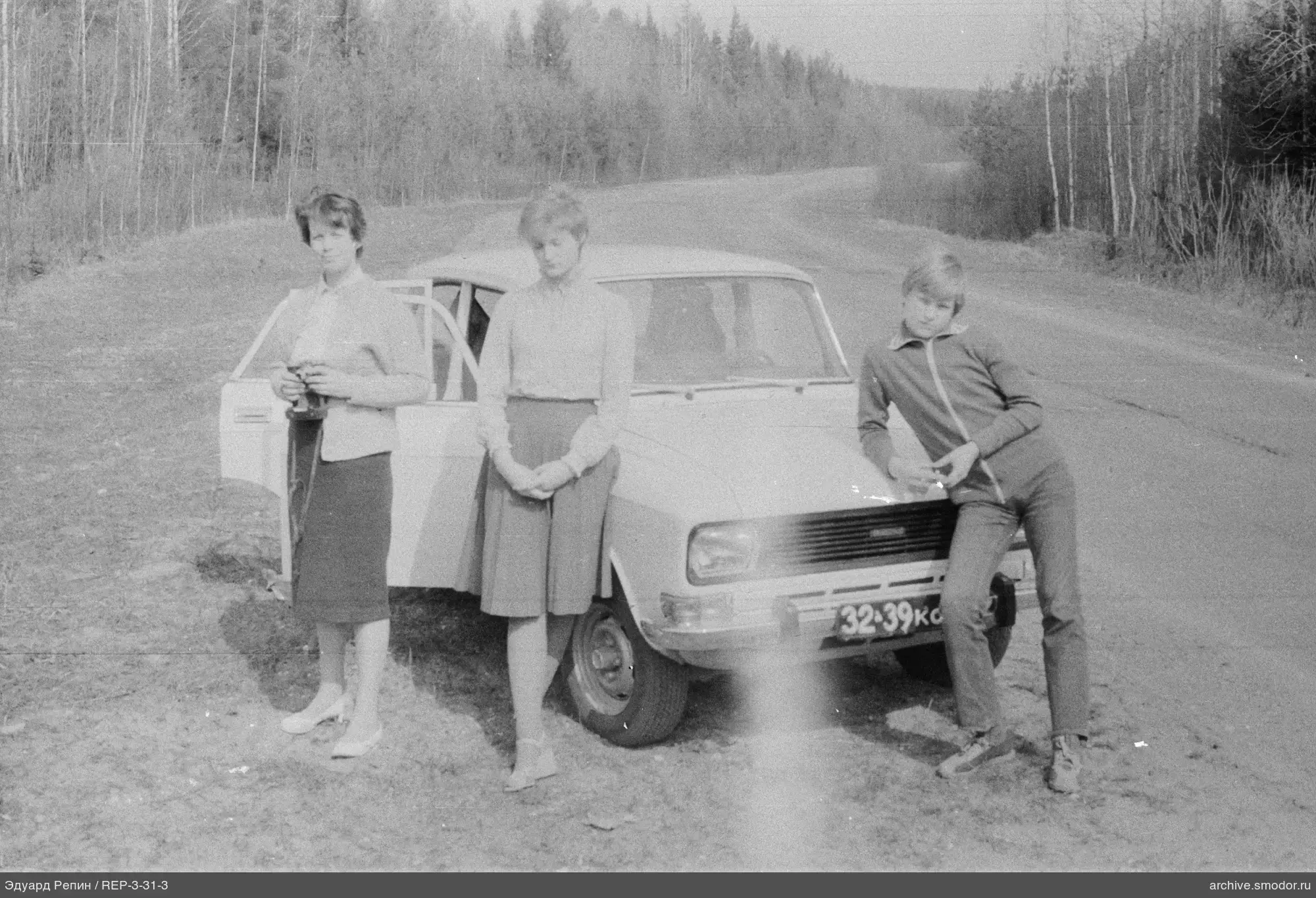 Gruppe bei einem weißen Auto am Straßenrand