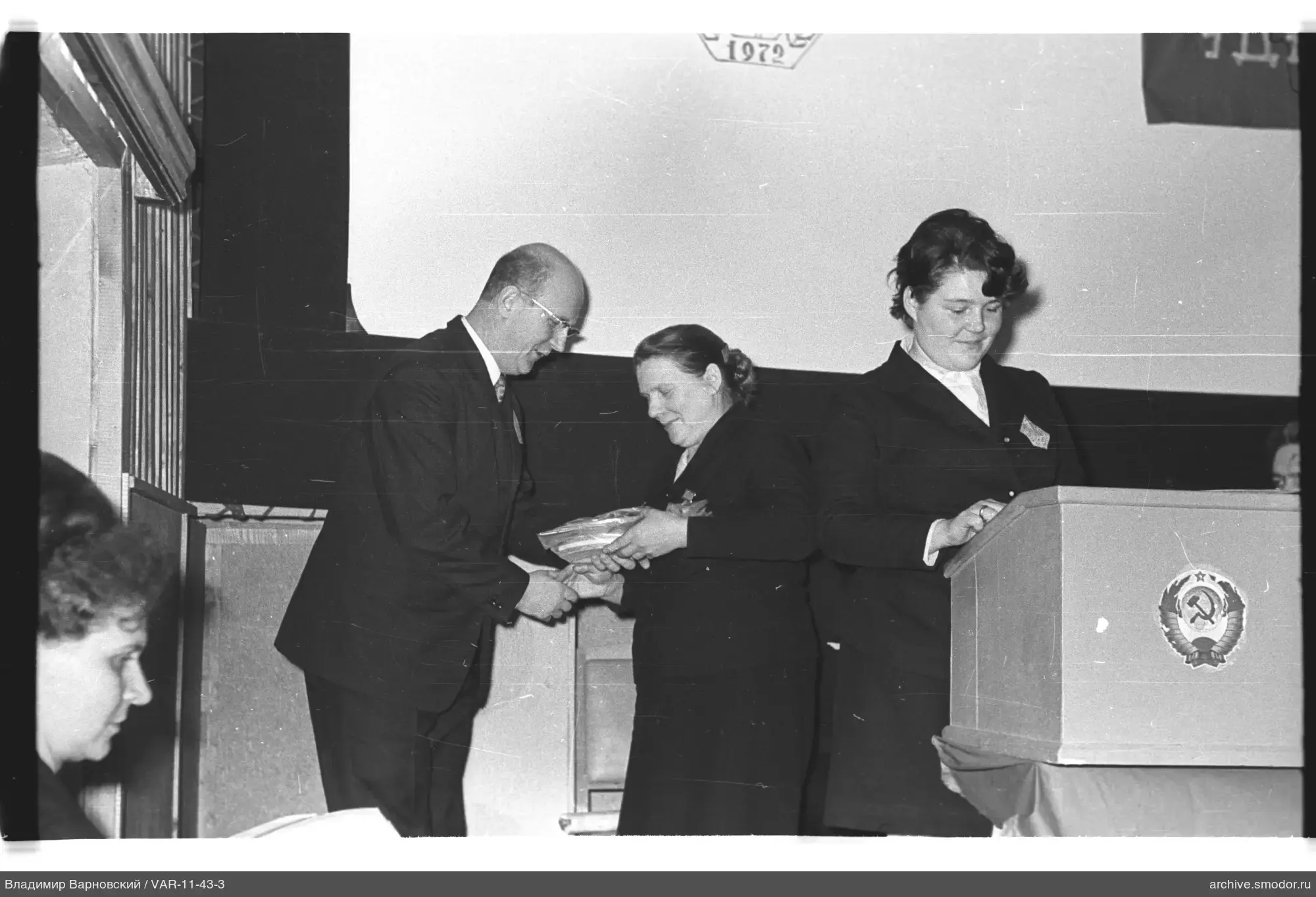 Man hands documents to woman