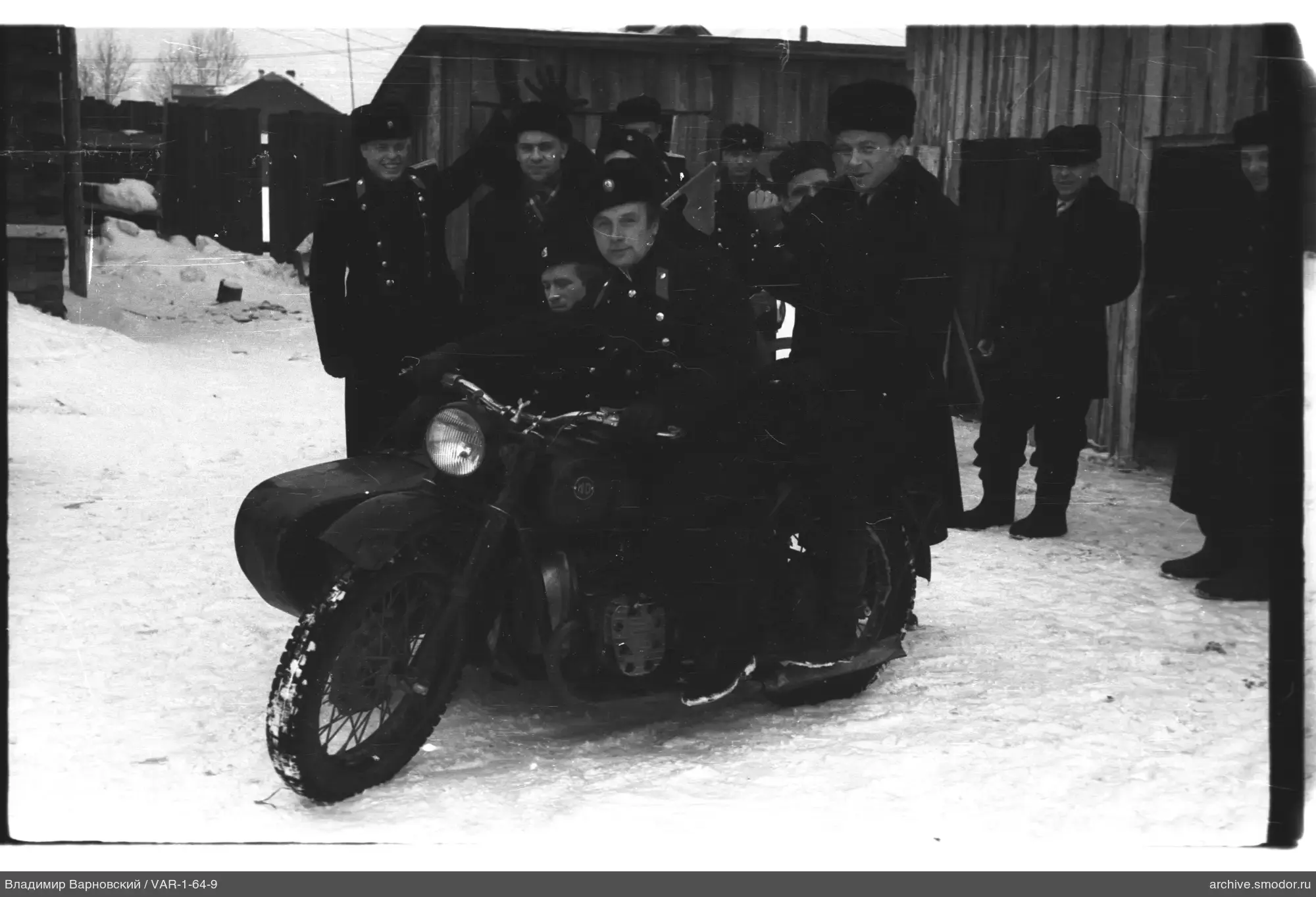 Men on snow near fence and buildings