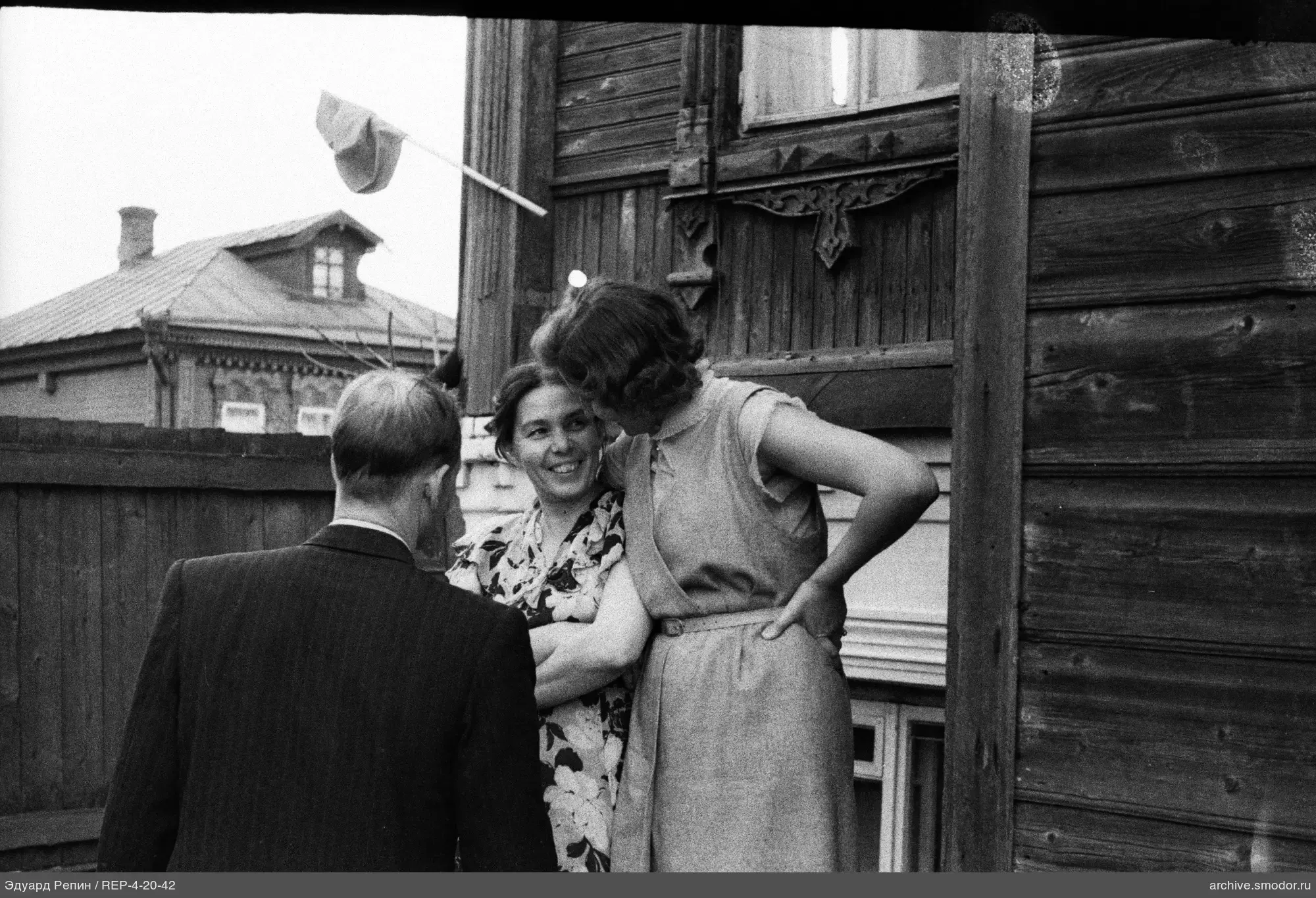 Gruppe vor einem Holzhaus mit geschnitztem Fensterrahmen