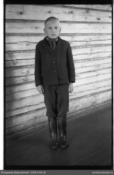 Junge mit dunklem Jacke an Holzwand
